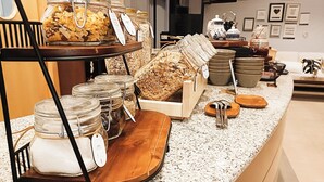 A breakfast buffet with various food items and utensils on a granite countertop. - Hotel Sercotel Portales (Logroño)