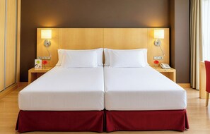 A double bed with a wooden headboard, two bedside tables with lamps, and a red skirted bed base. - Hotel Sercotel Portales (Logroño)