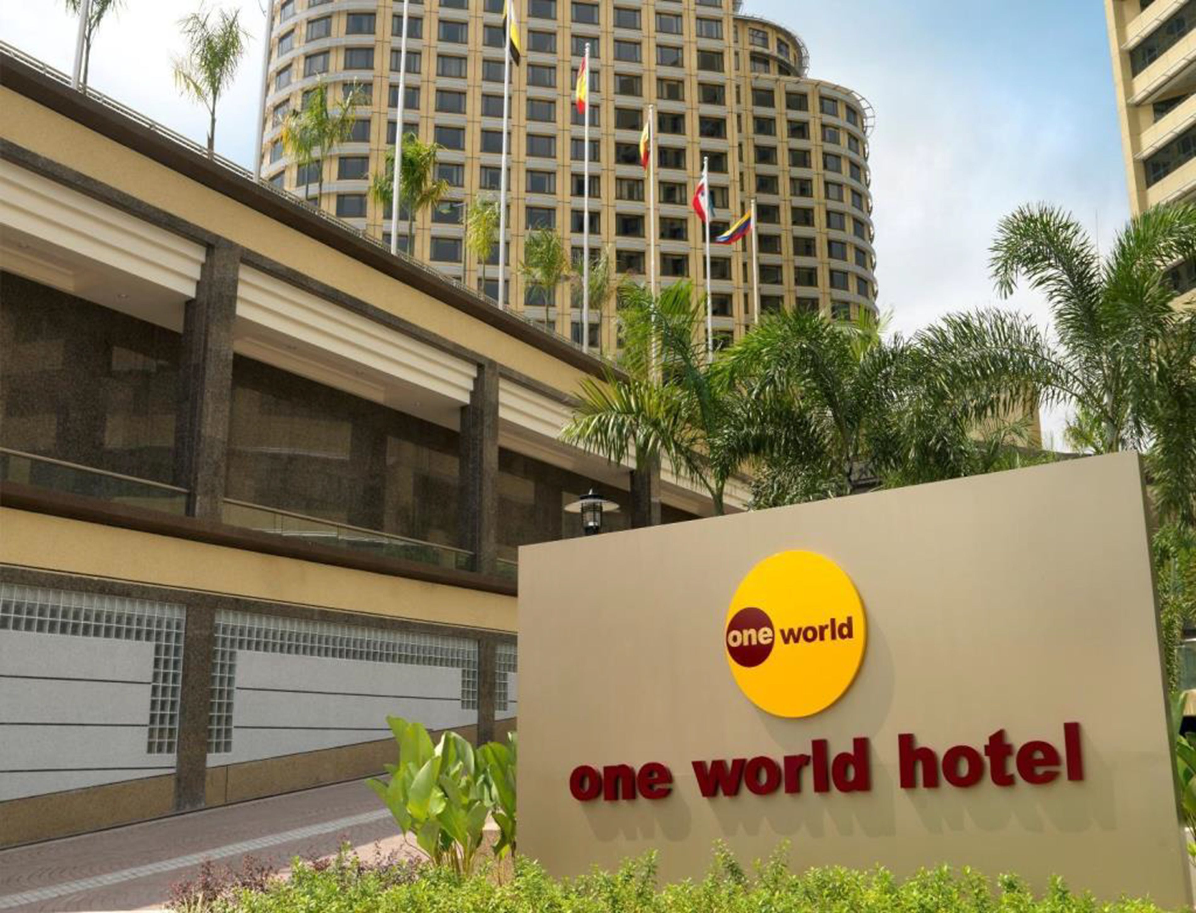 The exterior of the One World Hotel with a signboard displaying the hotel name.