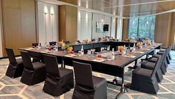 A conference room with a long table, black chairs, and a projector screen.