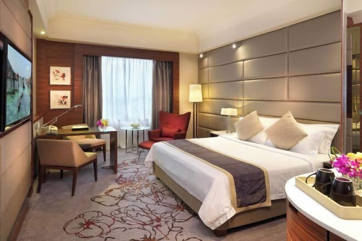 Una habitación de hotel con cama, escritorio, silla, mesita y televisor.