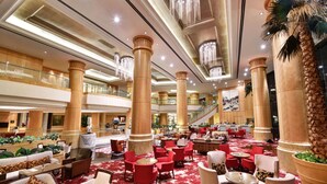 Un hall amplio con asientos rojos y blancos, columnas grandes y una alfombra roja.