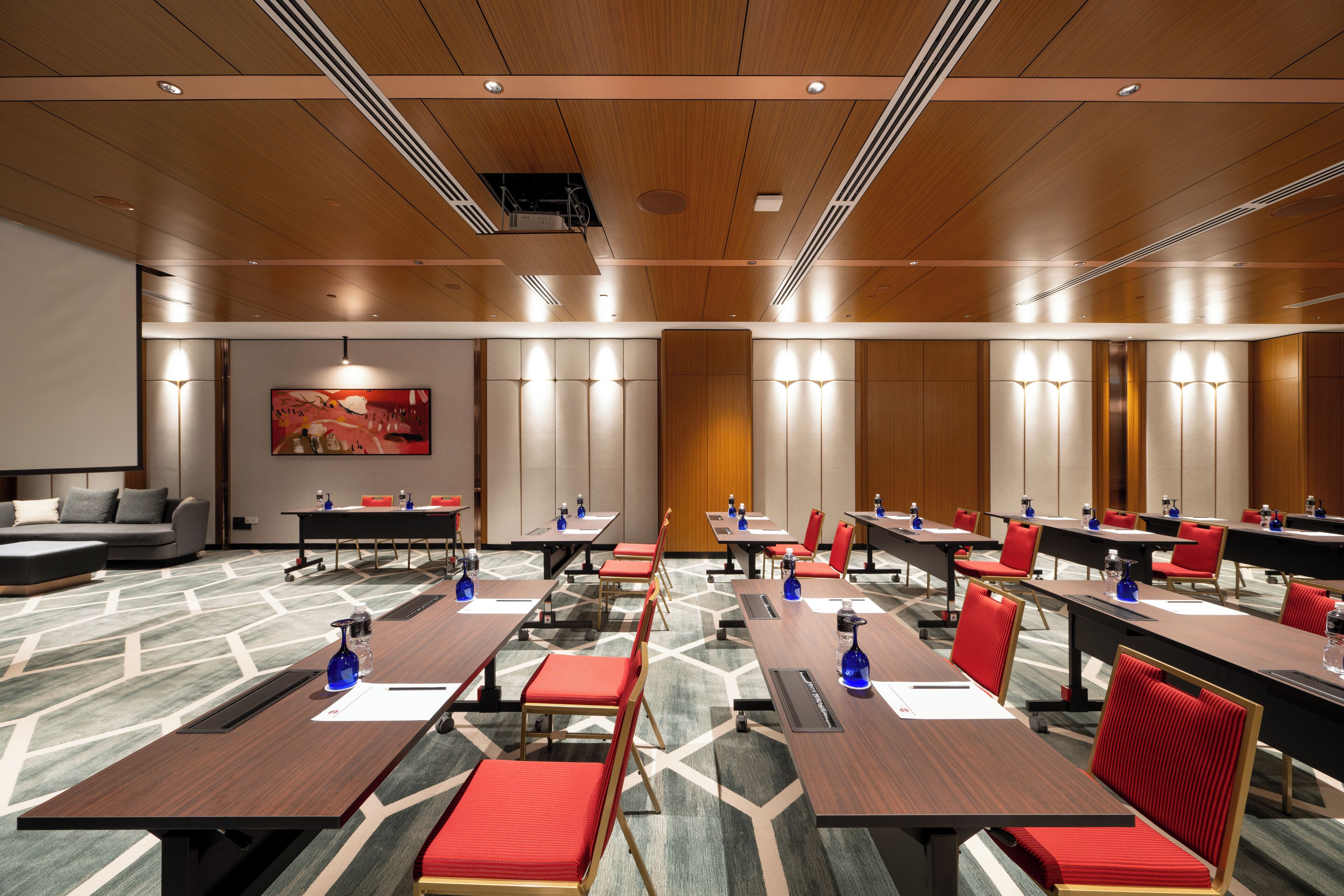 A conference room with multiple tables and chairs, equipped with water bottles and notepads.