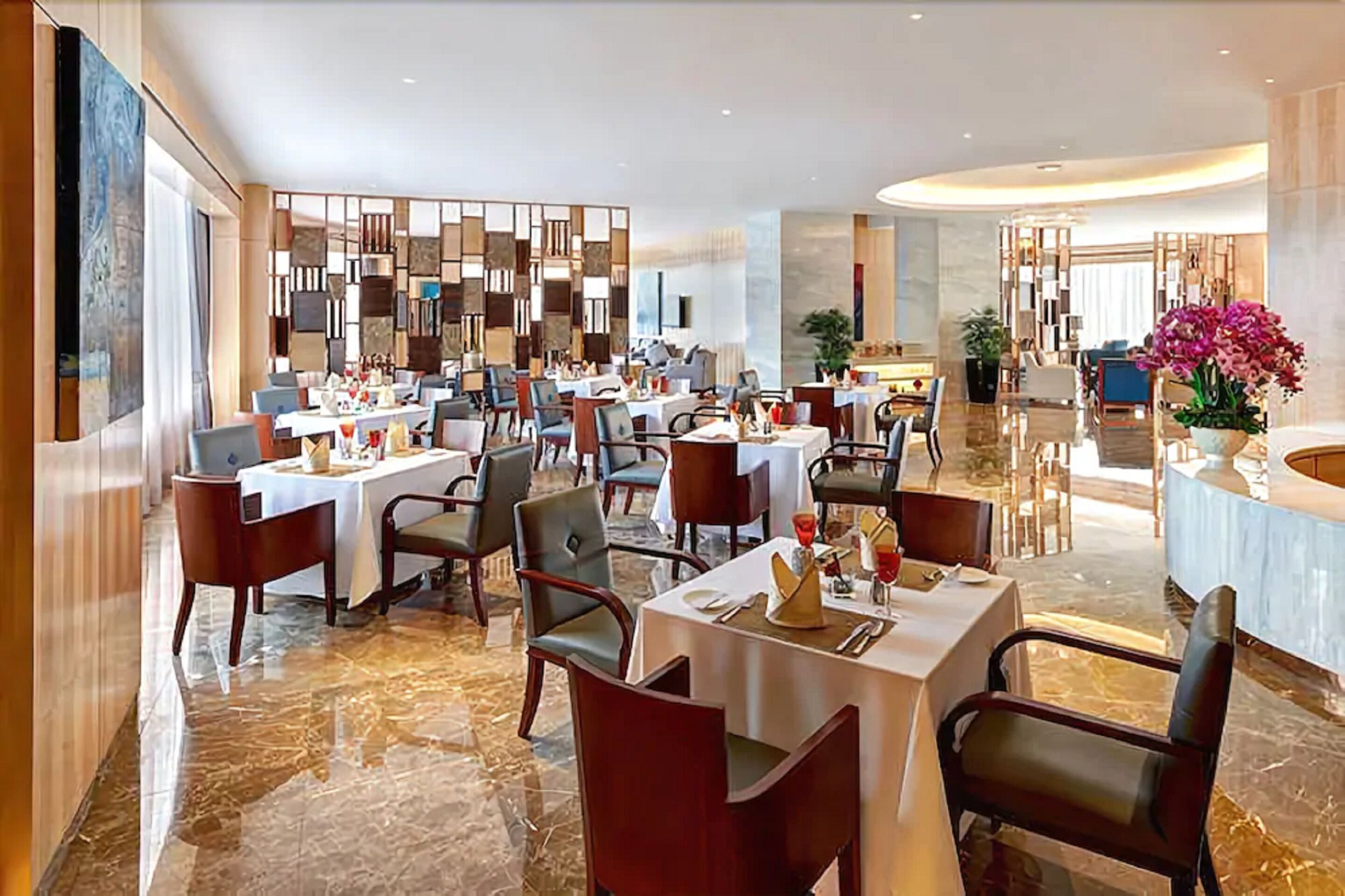 A modern restaurant with marble flooring, multiple dining tables, and contemporary decor.