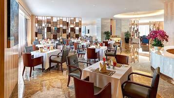 A modern restaurant with marble flooring, multiple dining tables, and contemporary decor.