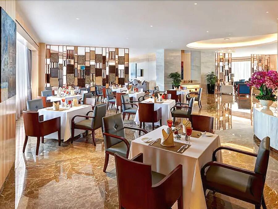 A modern restaurant with marble flooring, multiple dining tables, and contemporary decor.
