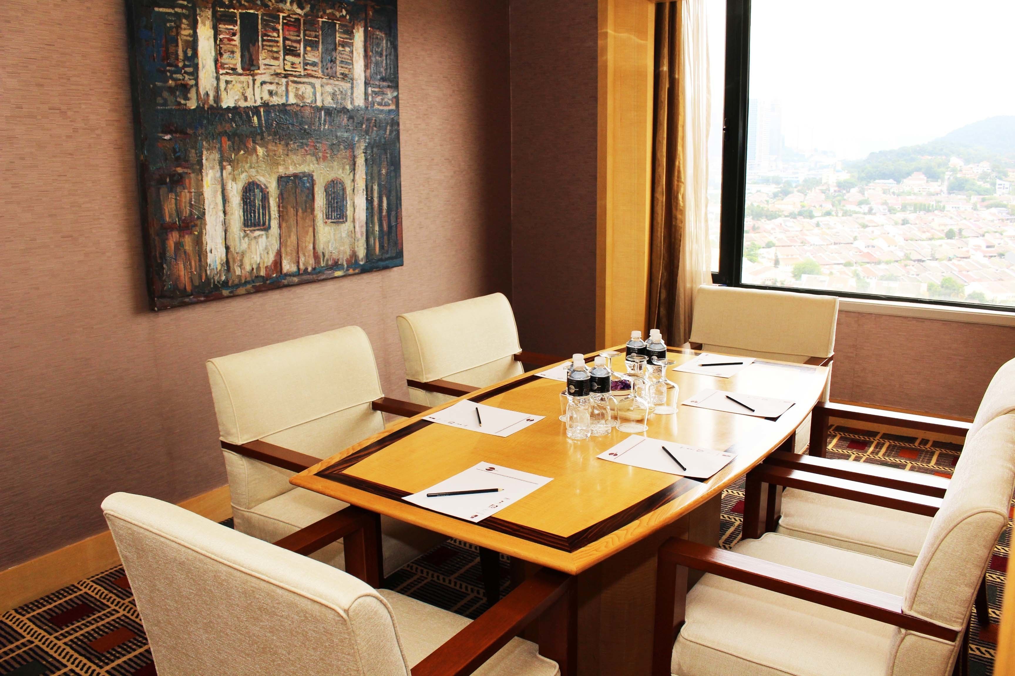 A conference room with a wooden table, four chairs, a painting on the wall, and a view of a cityscape through a window.