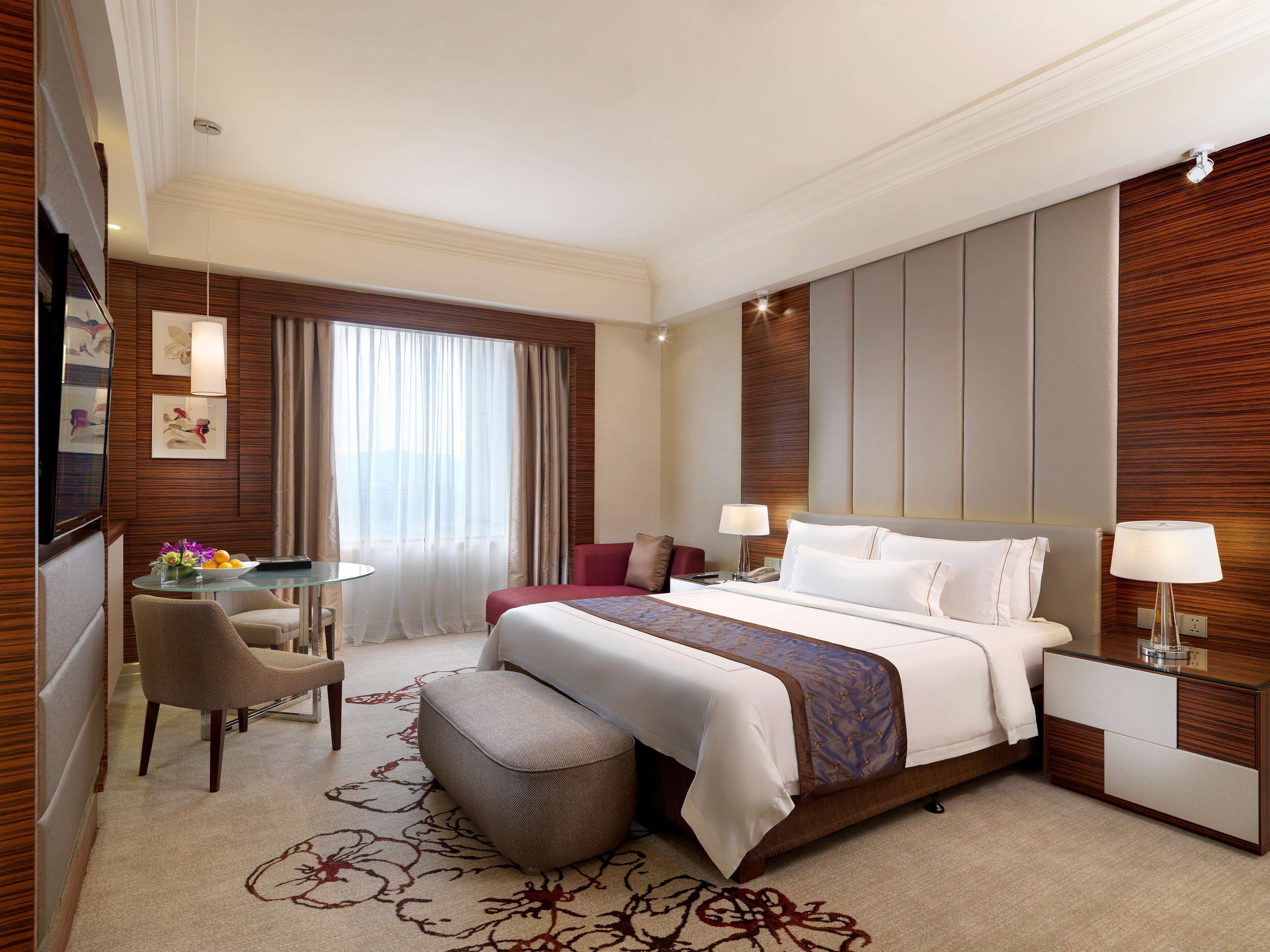 A hotel room with a large bed, a desk, a chair, and a small table.