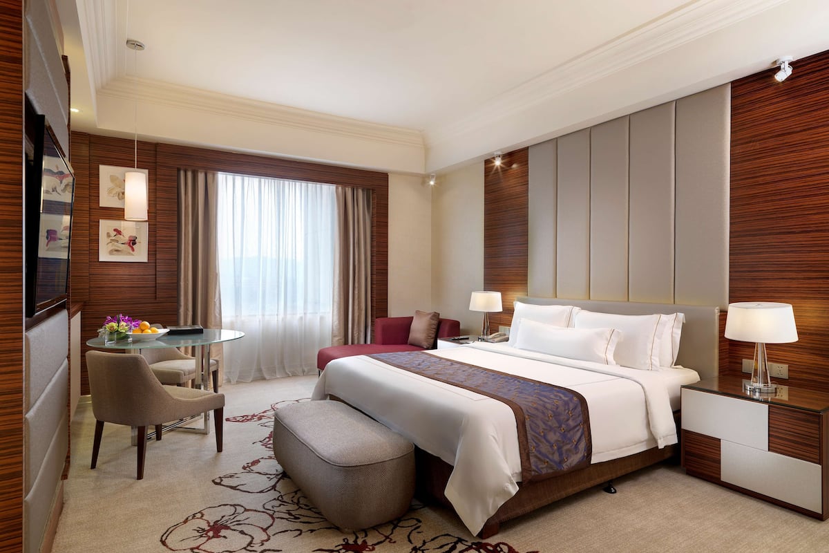 Una habitación de hotel con una cama grande, un escritorio, una silla y una mesita.