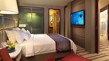 Une chambre d’hôtel avec un lit, une télévision, un bureau avec une lampe et une chaise rouge.