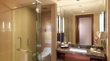 A modern bathroom with a glass shower enclosure, a toilet, a sink with a marble countertop, and a large mirror.
