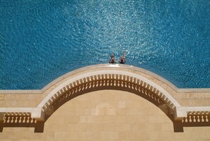 Una piscina con agua azul cristalina y un arco decorativo.