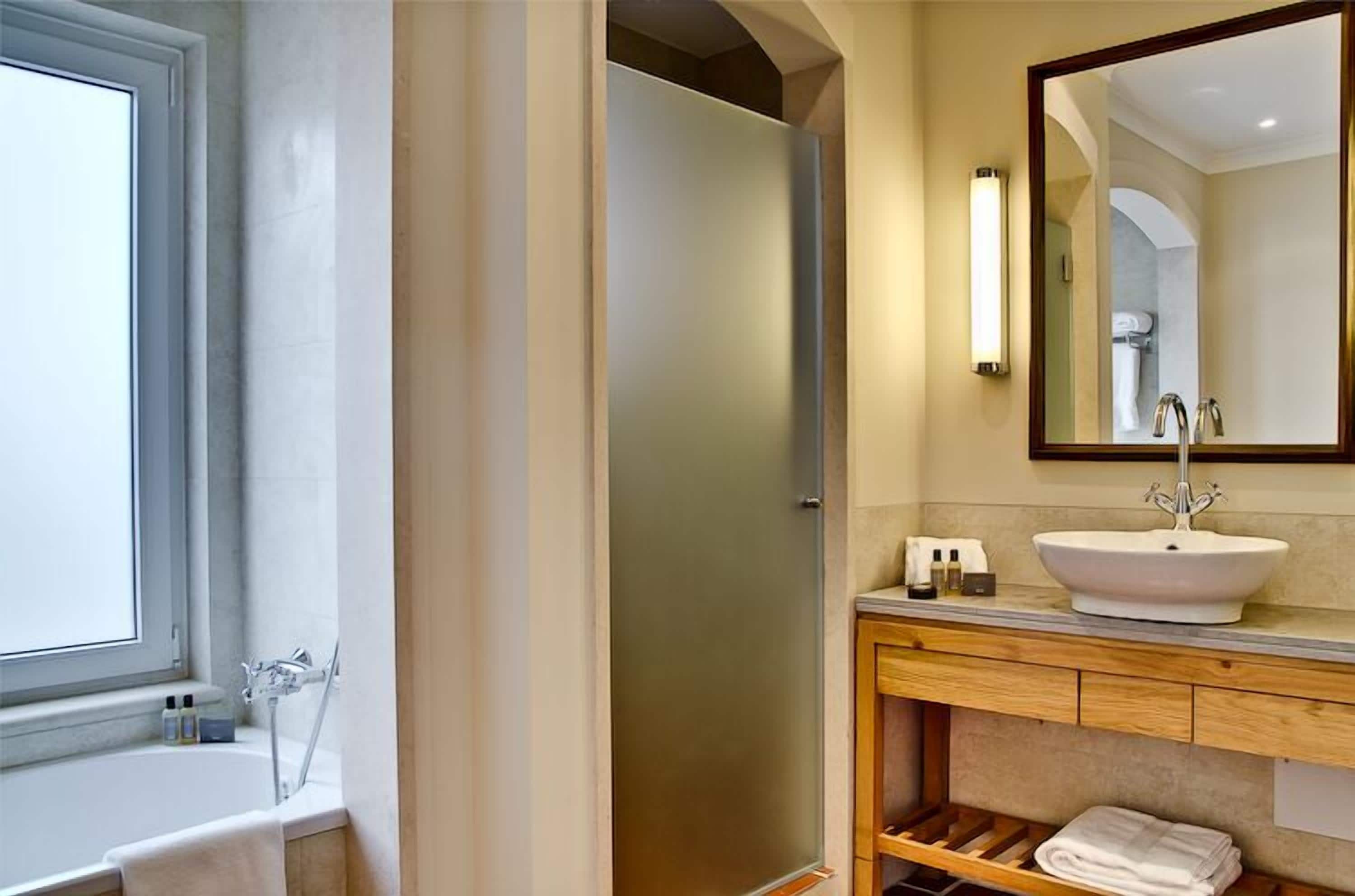 Un baño moderno con una bañera, un espejo grande y un tocador con lavamanos.