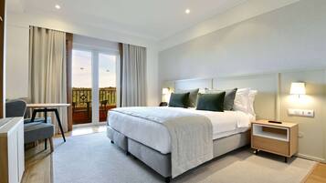 Une chambre d’hôtel moderne, dotée d’un grand lit, d’un bureau et offrant une vue sur l’extérieur.