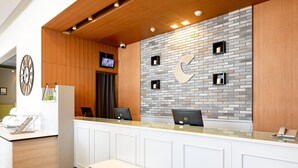 A reception area with a white counter, two computers, a clock, and a television on the wall. - Comfort Hotel Toyama (Toyama)