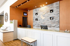 A reception area with a white counter, two computers, a clock, and a television on the wall. - Comfort Hotel Toyama (Toyama)