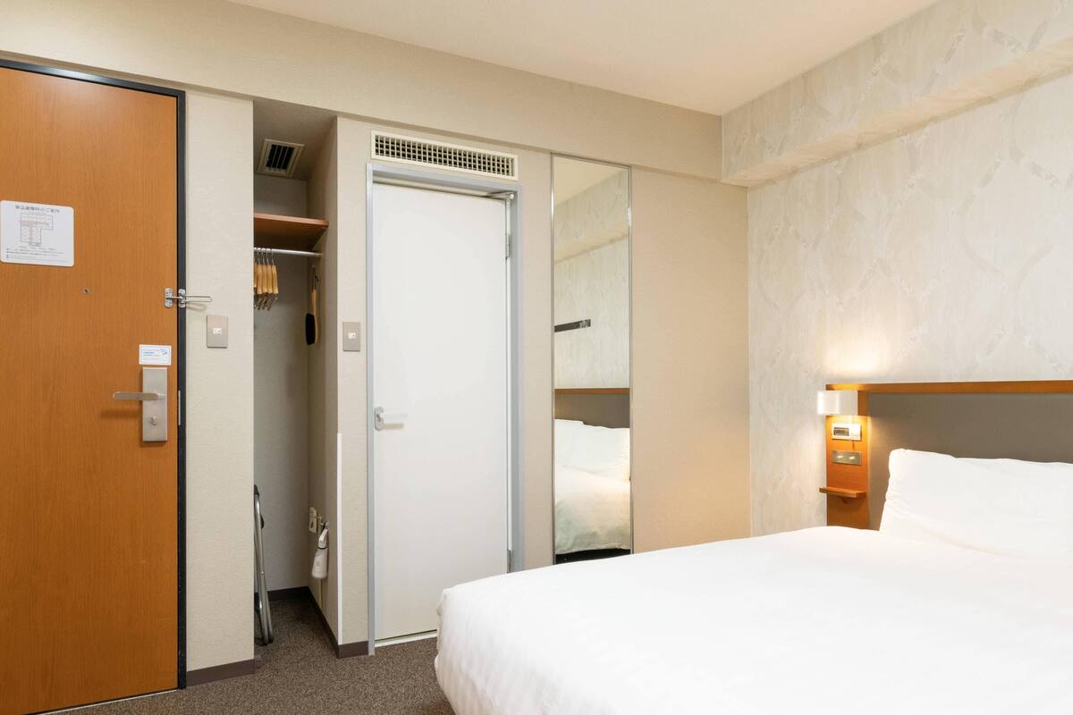 A hotel room with a bed, a closet, and a bathroom.