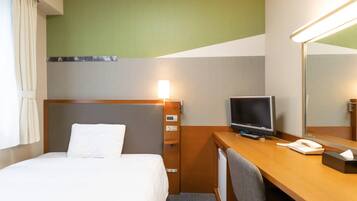 A hotel room with a bed, a desk with a computer, a mirror, and a TV.