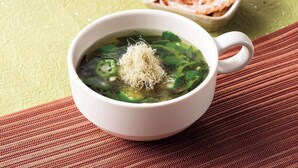 A bowl of soup with green vegetables and a white cup on a textured surface. - Comfort Hotel Toyama (Toyama)