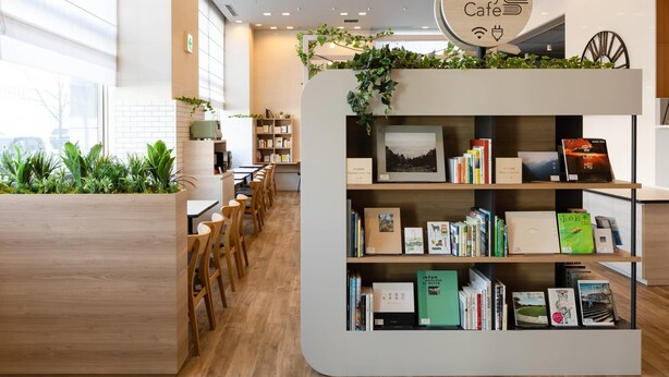 A library cafe with wooden furniture, bookshelves, and a sign indicating it is a library cafe. - Comfort Hotel Toyama (Toyama)