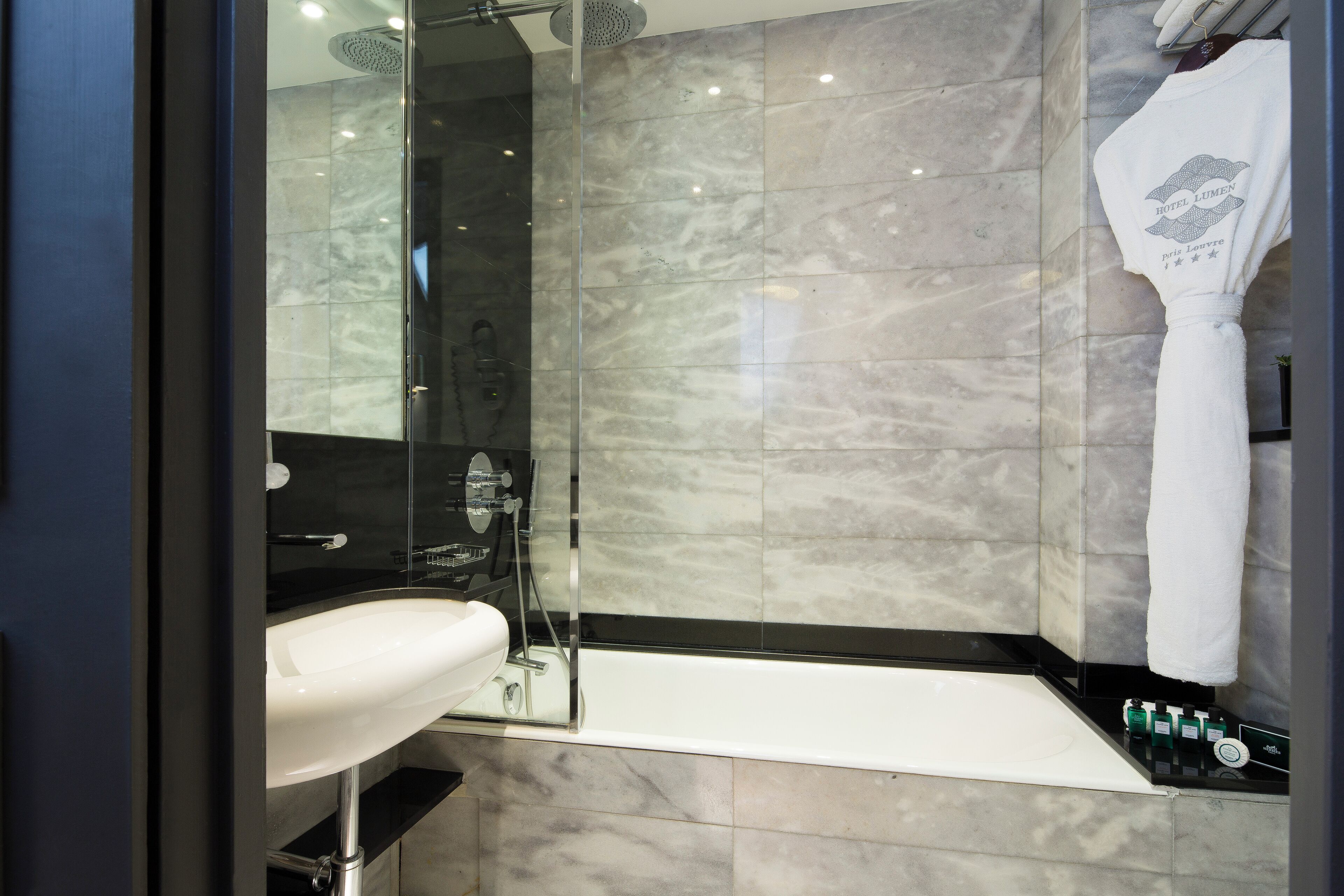 A modern bathroom with a glass-enclosed shower, a white sink, and a bathtub.