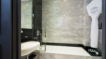 A modern bathroom with a glass-enclosed shower, a white sink, and a bathtub.