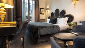 Habitación de hotel con una cama grande, un escritorio con lámpara, una silla y una mesita.