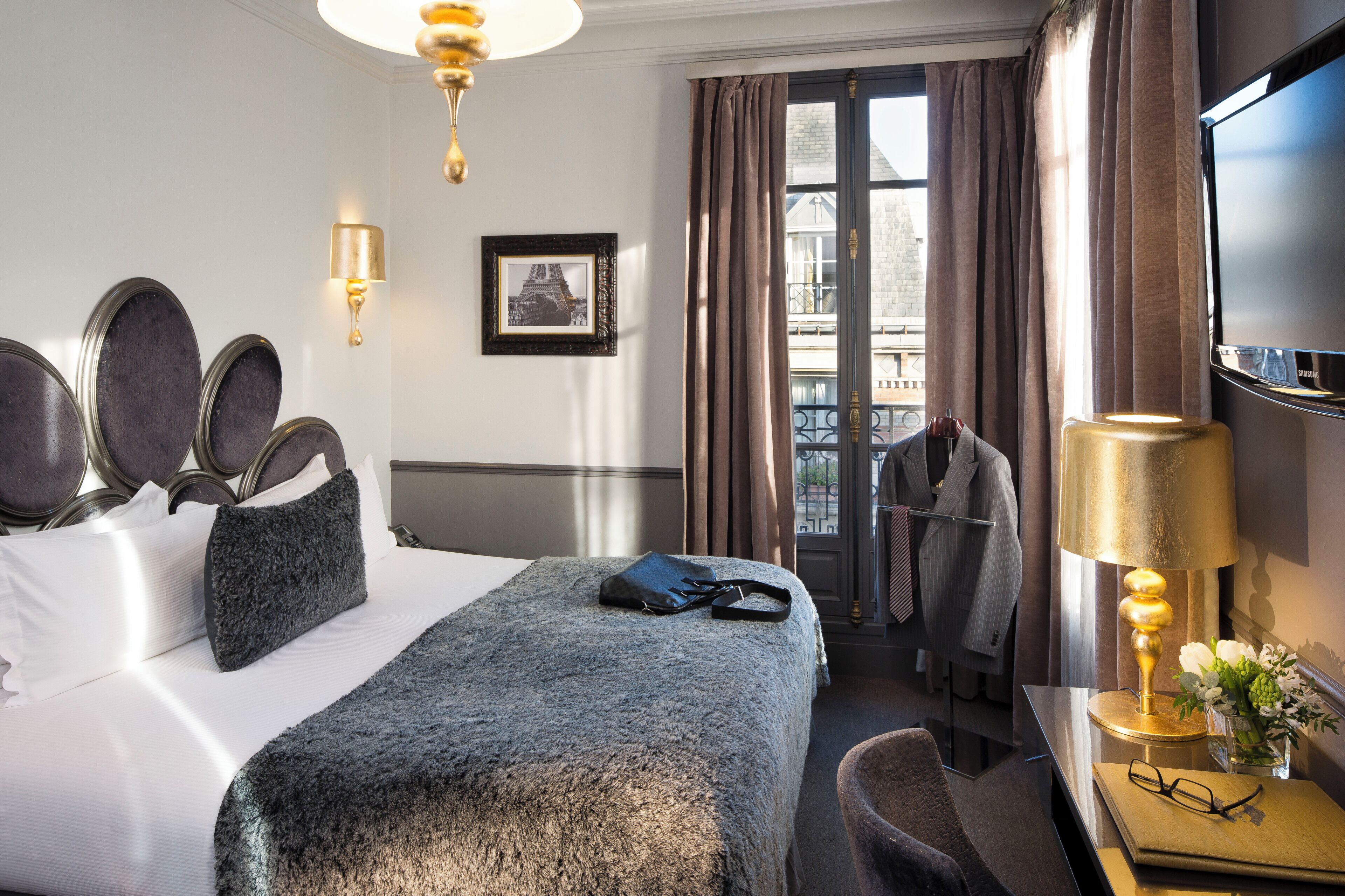 Une chambre d’hôtel avec un lit, un bureau doté d’une lampe, une télévision et une vue sur la ville.