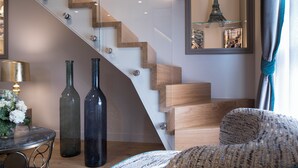 Un interior moderno con una escalera de madera, una mesa redonda con jarrones y un sofá.