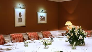 Ein formeller Speisesaal mit einem langen Tisch, der für eine Mahlzeit gedeckt ist, Kunstwerken an den Wänden und einer floralen Tischdekoration.