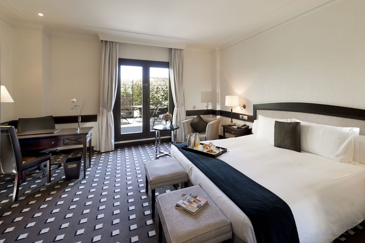 Una habitación de hotel con una cama grande, un escritorio, una silla y una mesita.