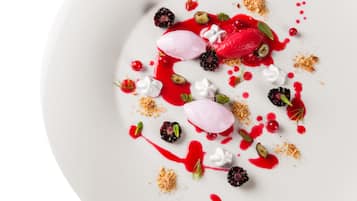 A dessert plate with various fruits, meringue, and a scoop of ice cream.