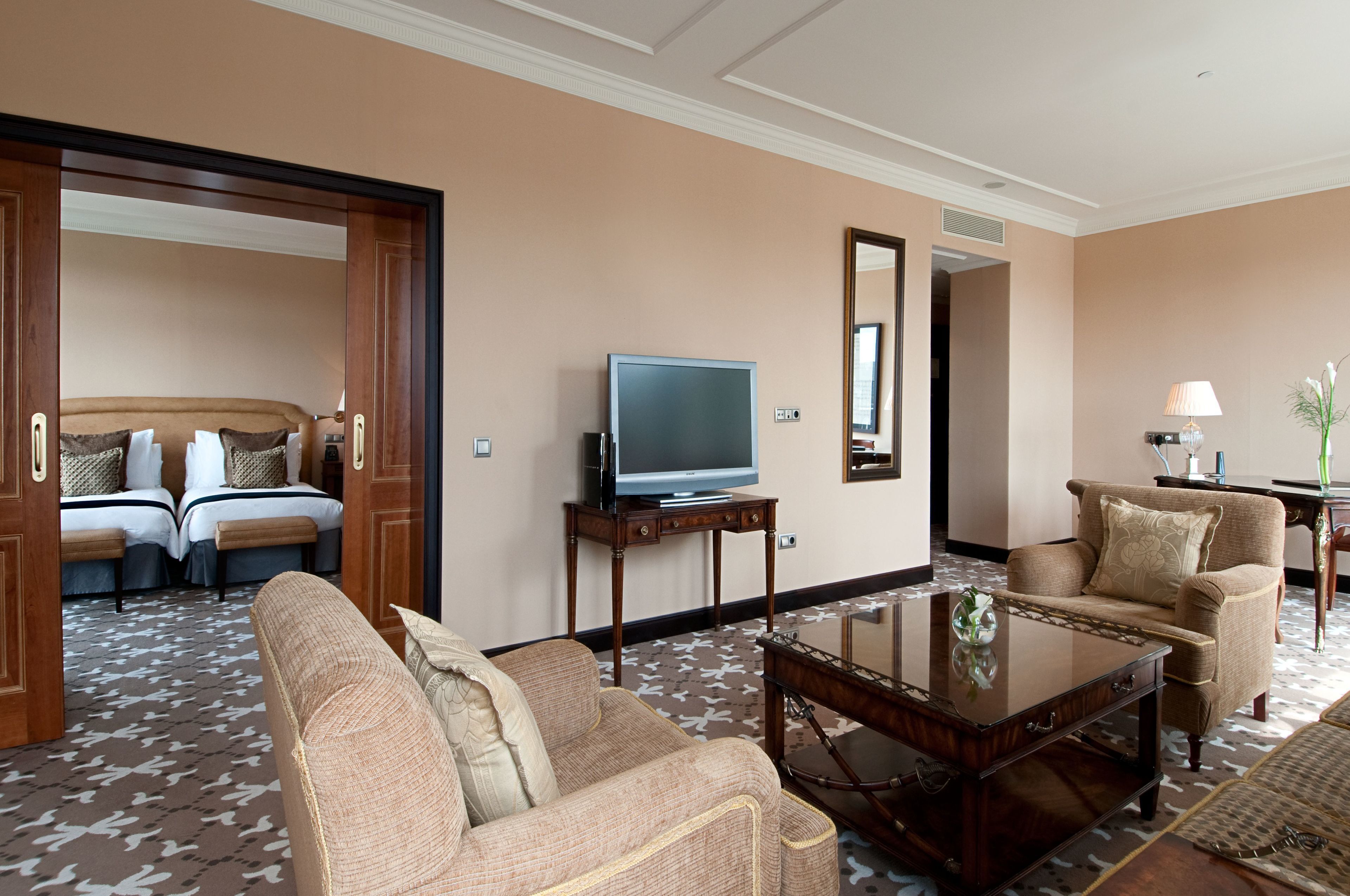 Una habitación de hotel con sofá, sillón, televisión y una mesita.