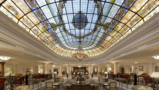 Un amplio vestíbulo con techo alto, vidrieras decorativas y un candelabro central.
