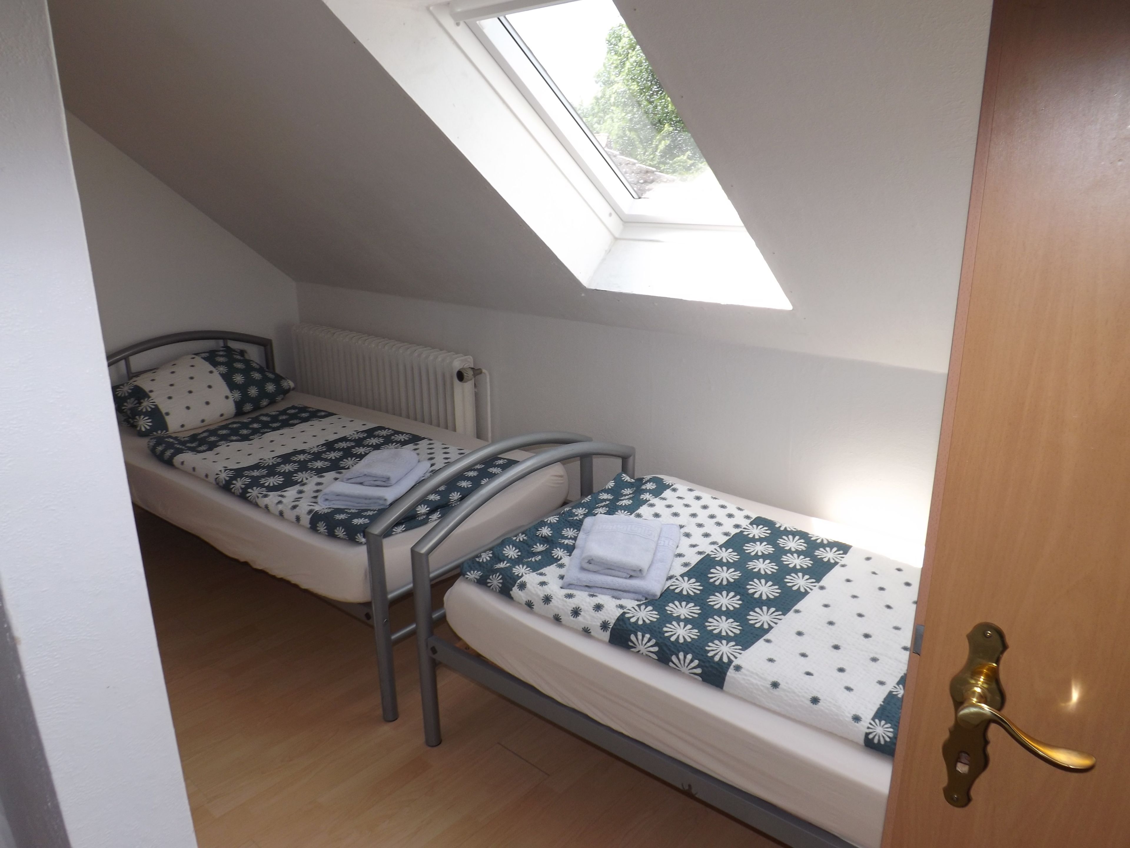 Un petit logement composé d’une seule pièce, avec deux lits, une lucarne et un plancher en bois.