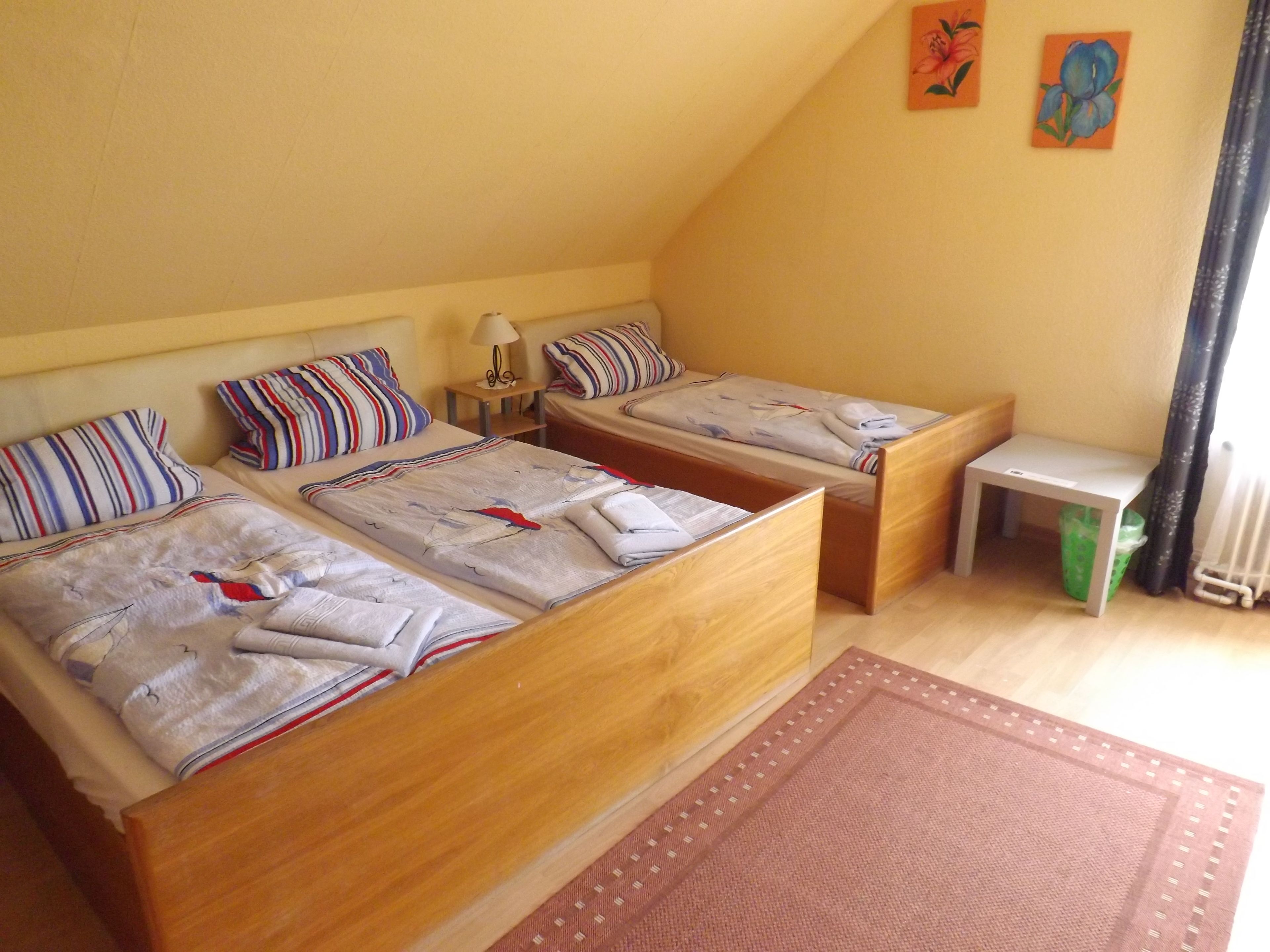 Una habitación con dos camas de madera, una mesita y un radiador.
