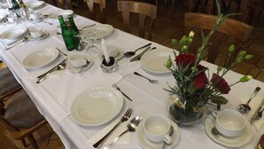 A dining table set with white plates, silverware, and a vase with red roses. - Hotel zum Norden (Jagel)