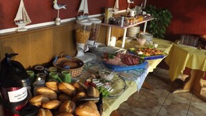 A buffet table with various food items, including breads, salads, and meats, along with condiments and utensils. - Hotel zum Norden (Jagel)