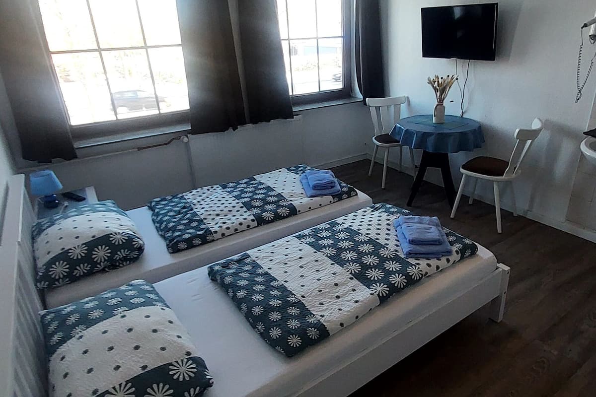 Een kamer met twee bedden, een televisie, een tafeltje en een stoel.