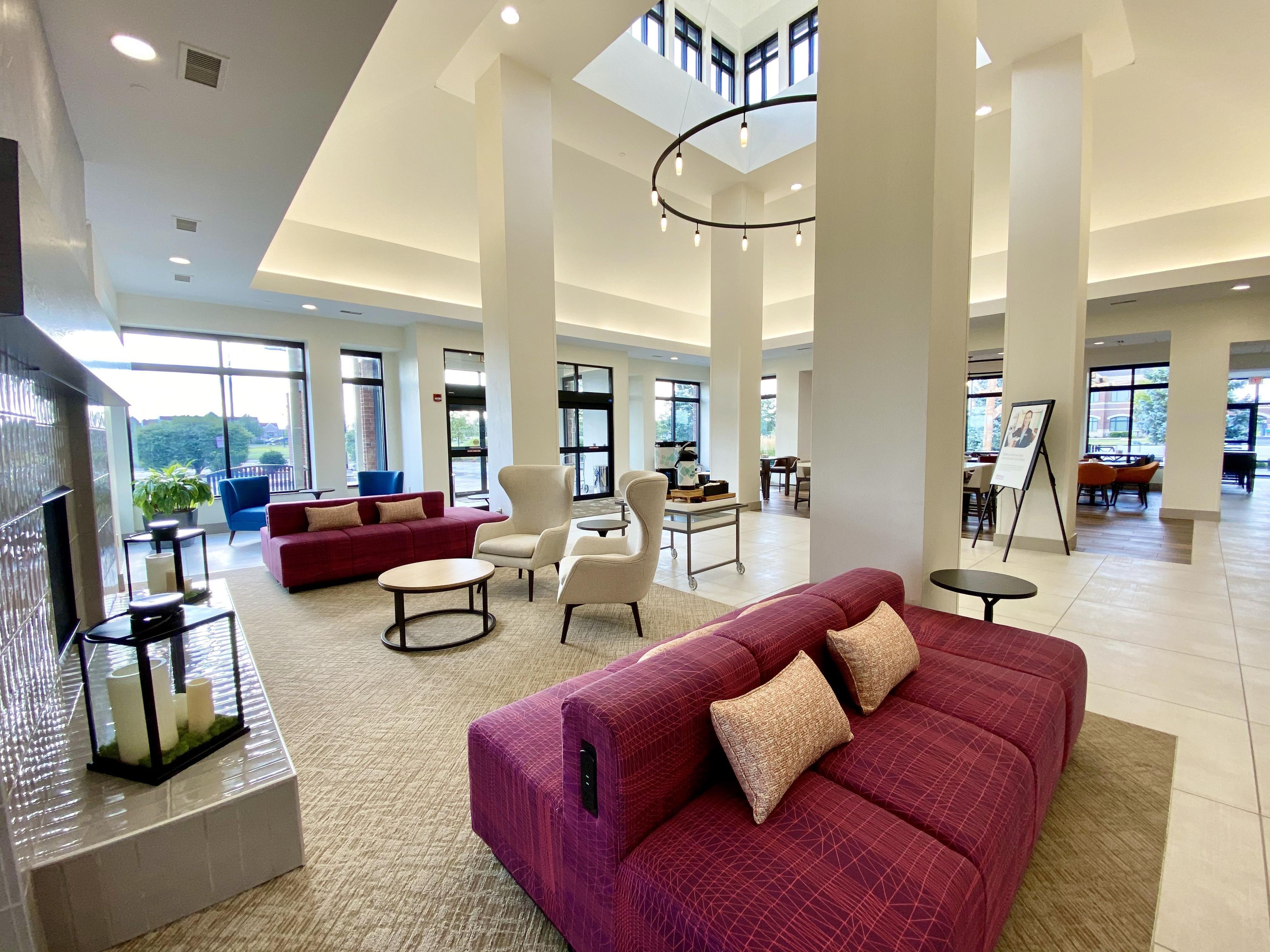 Eine geräumige Lobby mit einem roten Sofa, einem Couchtisch und einem Kamin.