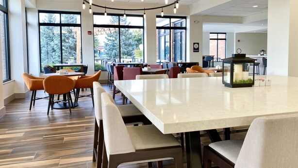 A spacious indoor area with large windows, a central table, and multiple seating arrangements. - Hilton Garden Inn Oconomowoc (Oconomowoc)