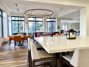 A spacious indoor area with large windows, a central table, and multiple seating arrangements. - Hilton Garden Inn Oconomowoc (Oconomowoc)