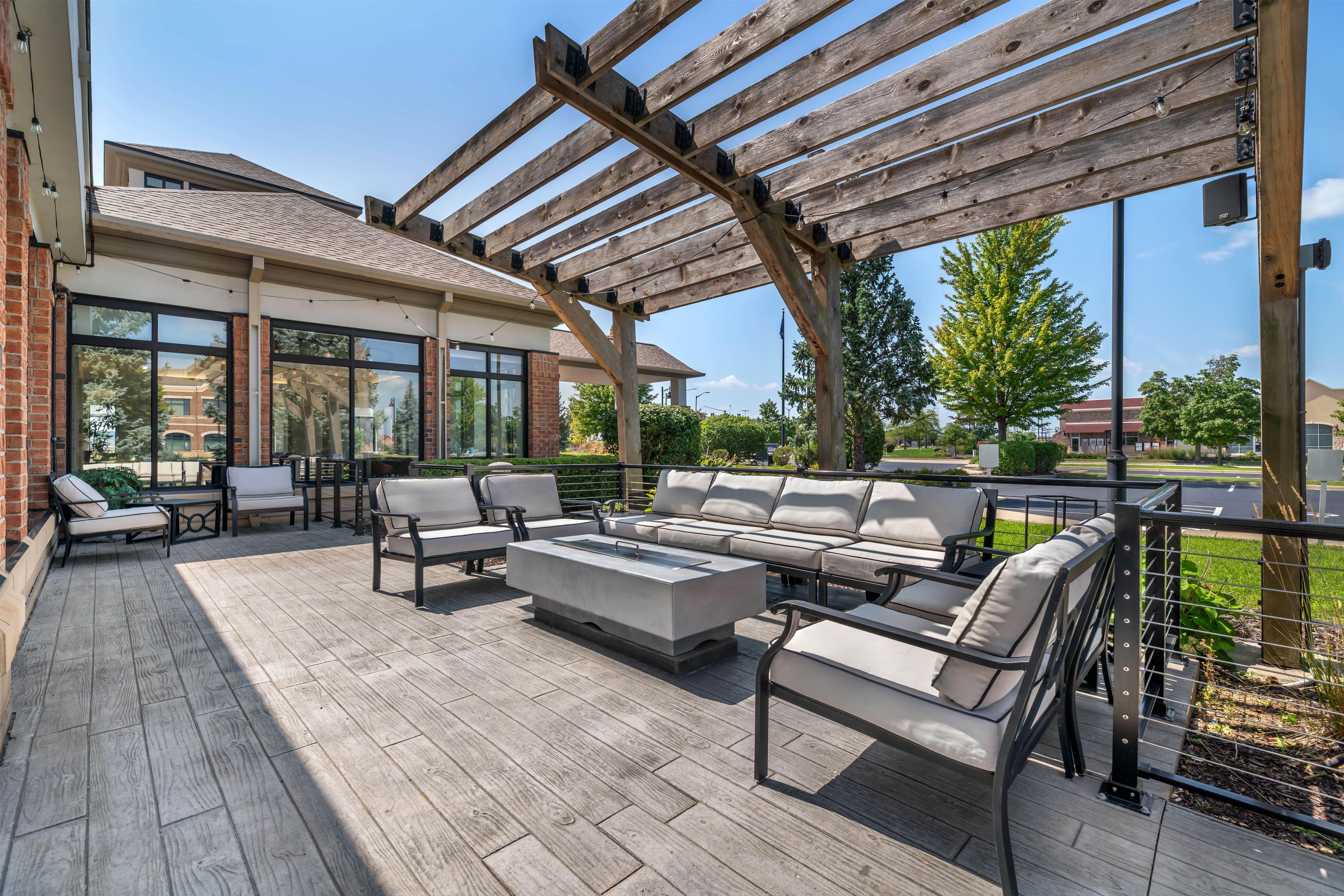 An outdoor patio with a wooden pergola, seating area, and a view of the surrounding buildings.