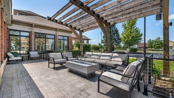 An outdoor patio with a wooden pergola, seating area, and a view of the surrounding buildings.