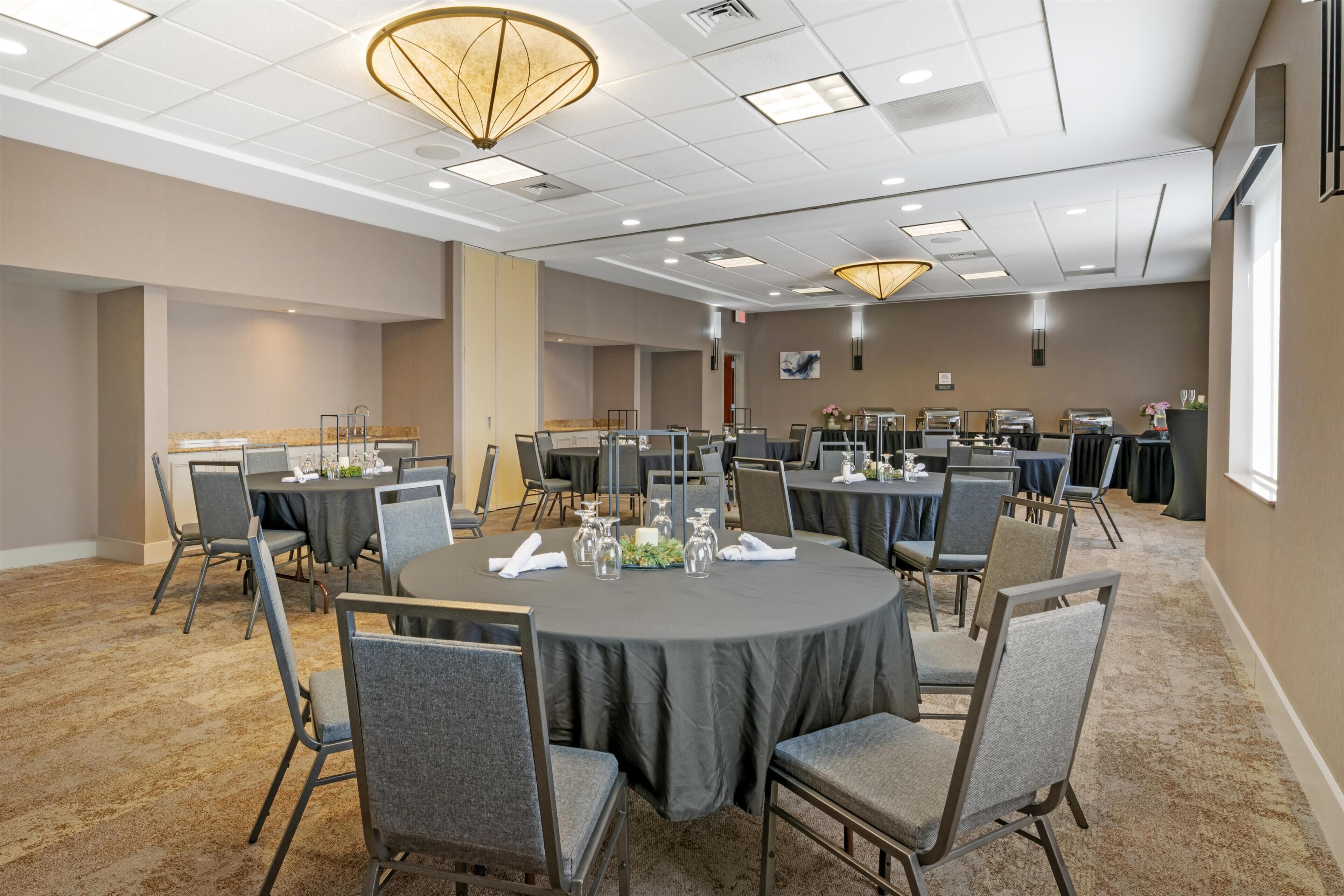 A conference room with round tables, chairs, and a ceiling with recessed lighting.