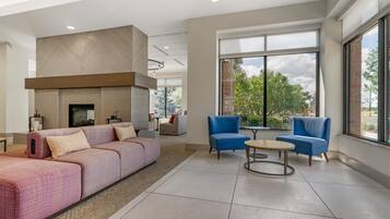 A modern living room with a fireplace, sofas, and a large window offering a view of the outdoors.