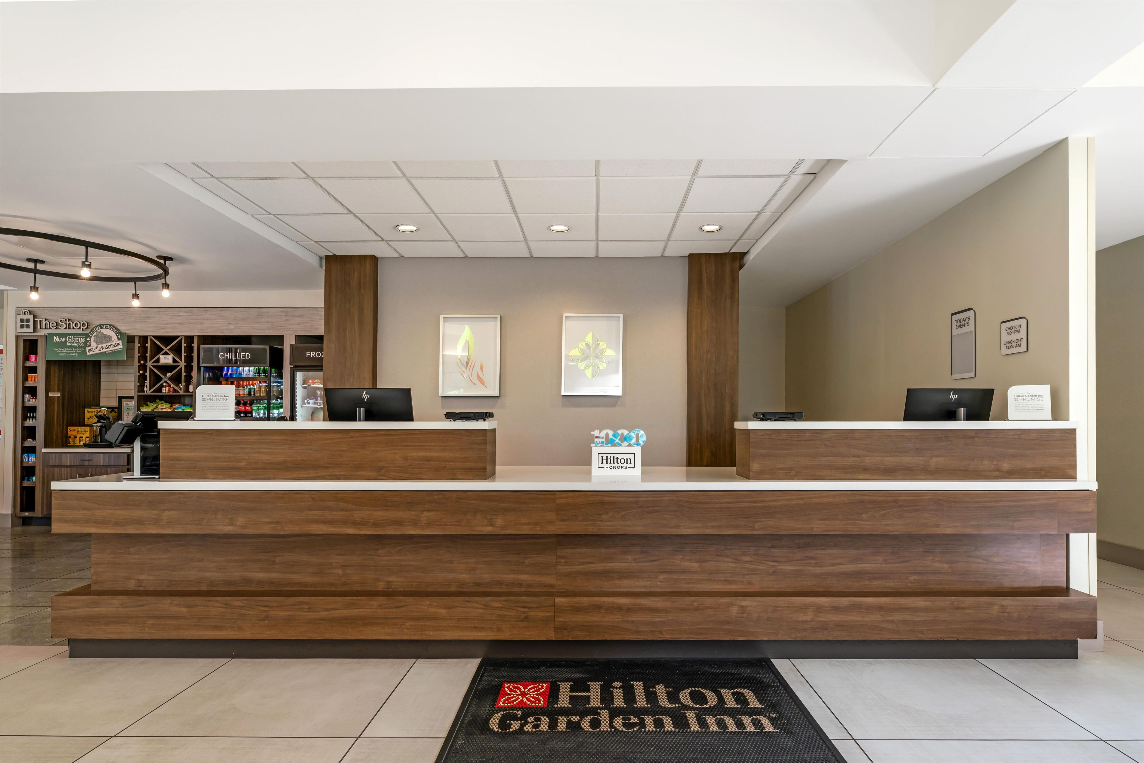 A hotel reception desk with a modern design, a digital screen, and a check-in/out counter.