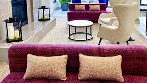 A modern living room with a fireplace, a sofa set, and a television. - Hilton Garden Inn Oconomowoc (Oconomowoc)