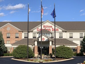 A Hilton Garden Inn with a brick facade, a central entrance, and two flagpoles. - Hilton Garden Inn Oconomowoc (Oconomowoc)