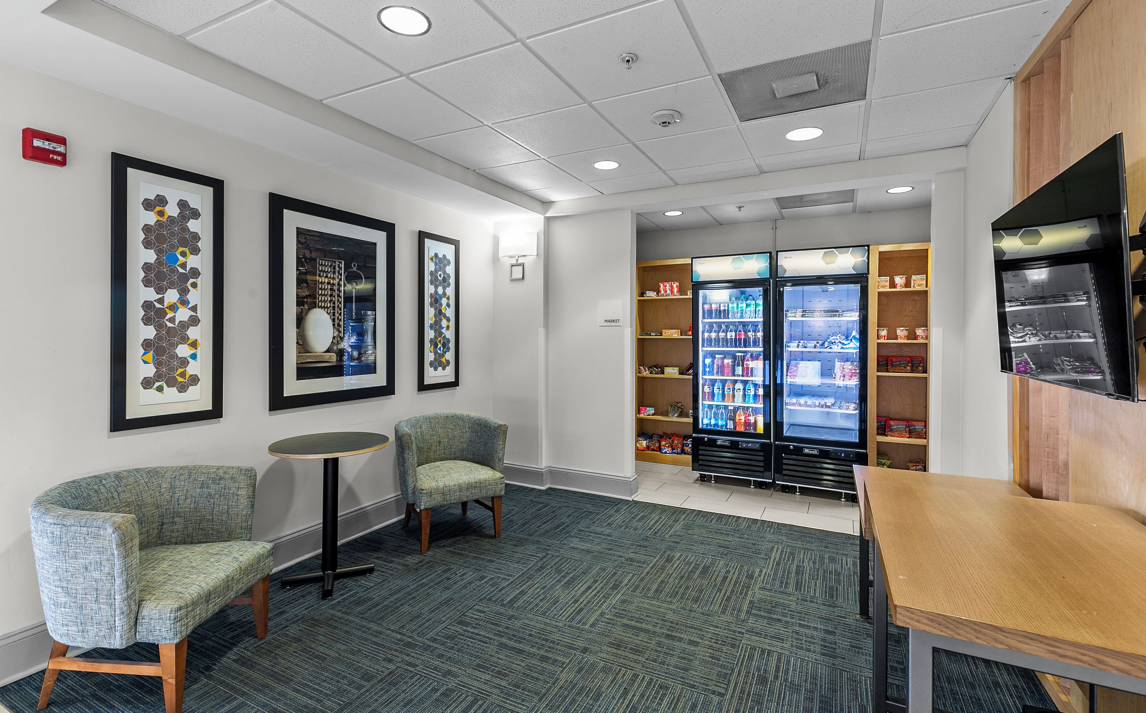 A lobby with seating, a vending machine, and a wall-mounted fire alarm.